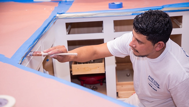 A picture of a Five Star Painting technician painting cabinets.