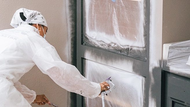 A picture of a Five Star Painting technician refinishing cabinets.