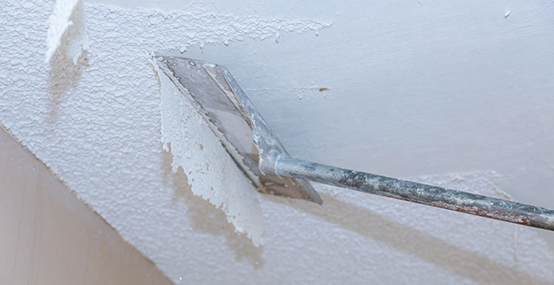 A closeup picture of a scraper removing popcorn ceiling.