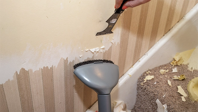 A steamer loosens wallpaper during a wallpaper removal job.