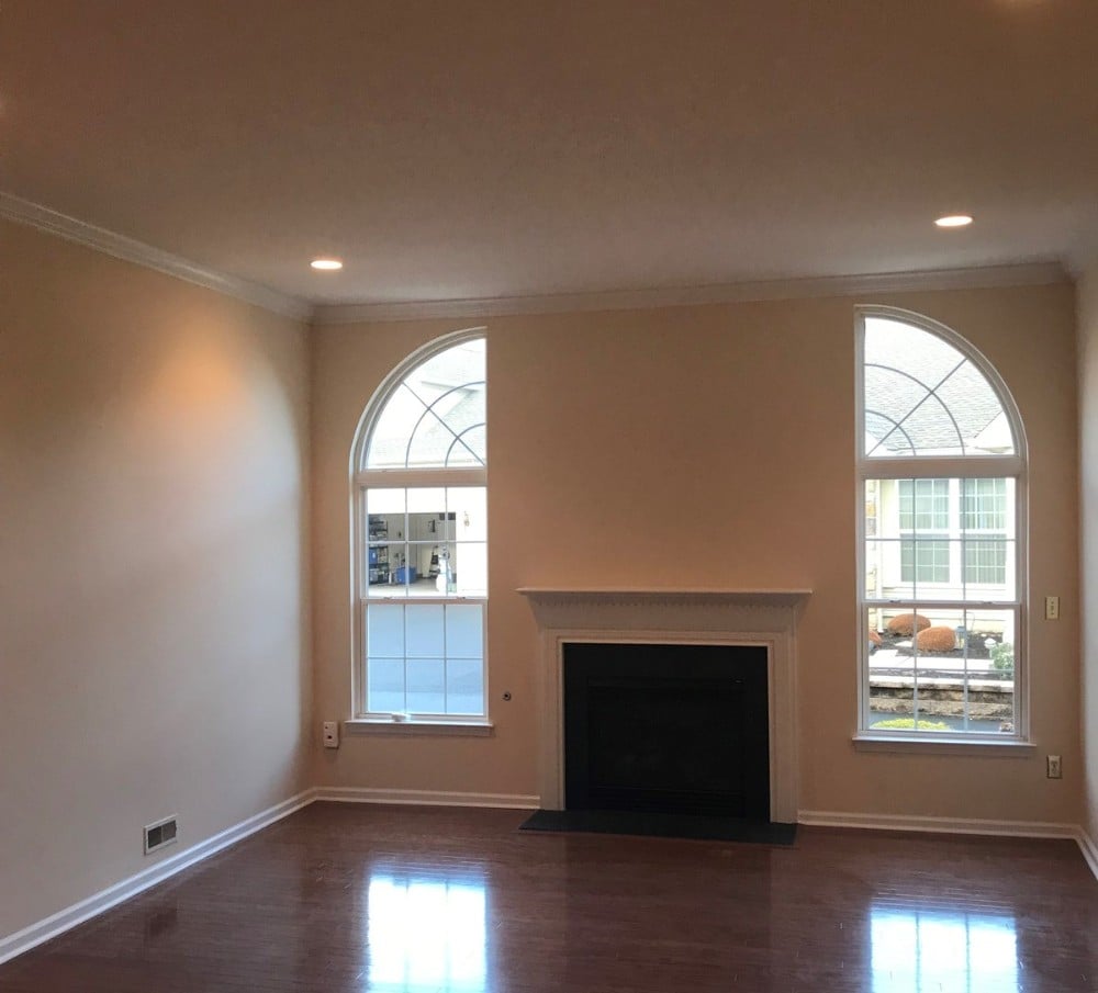 Creamy colored walls two white windows fireplace wood floors white trim