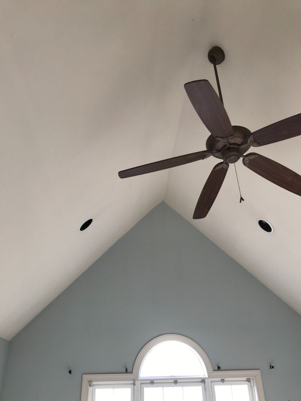 Blue walls white ceilings large window with white trim and a brown fan