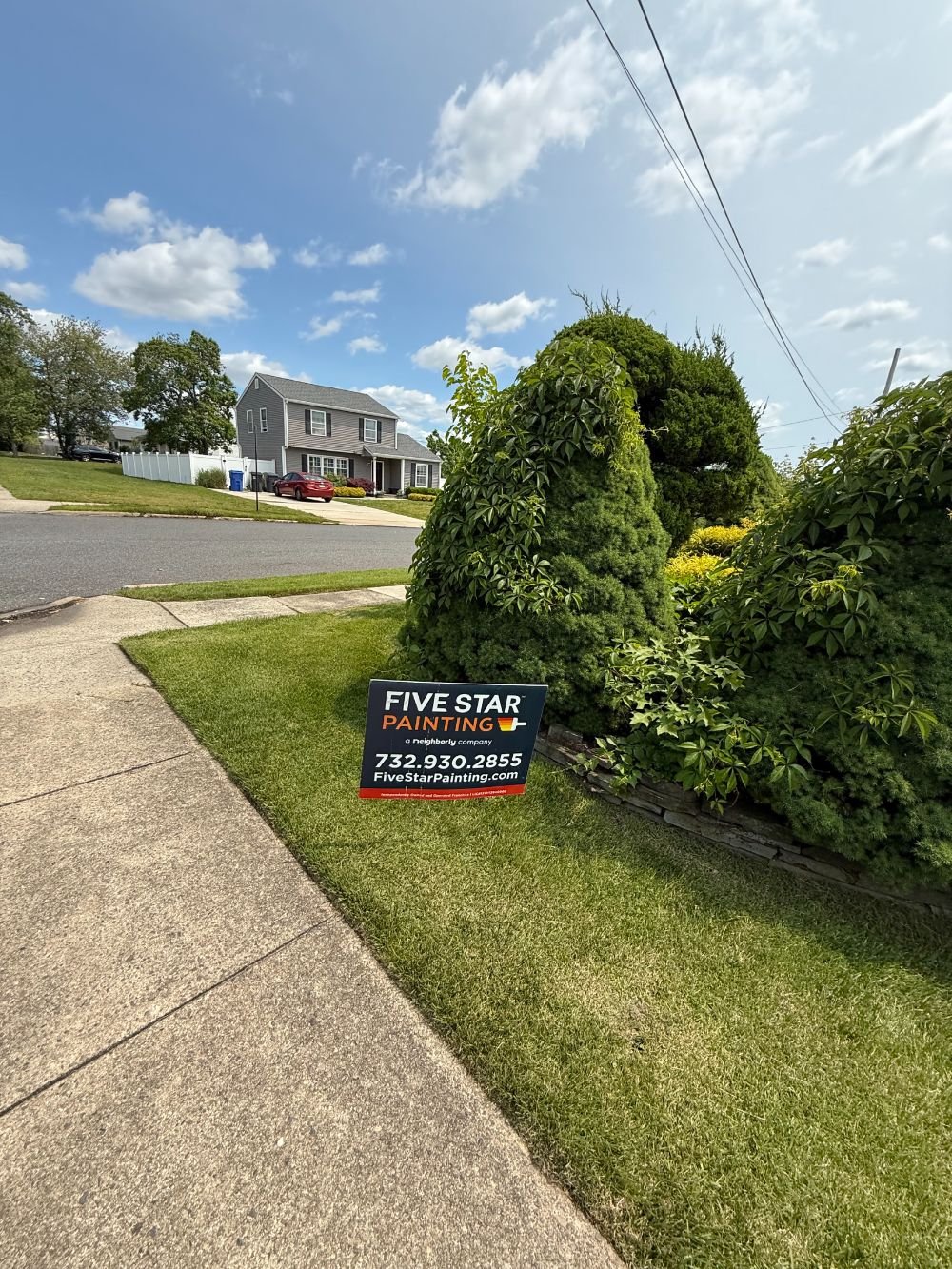 Five Star Painting yard sign on a green lawn in Toms River, NJ, placed in front of a freshly painted gray home. Promotes professional exterior painting services and local brand visibility.
