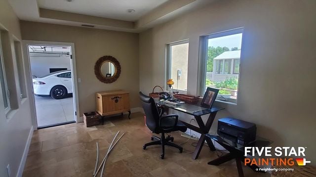 beige office room with a glass desk and black chair