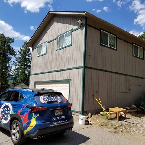 grey house with green trims and five star painting car out front