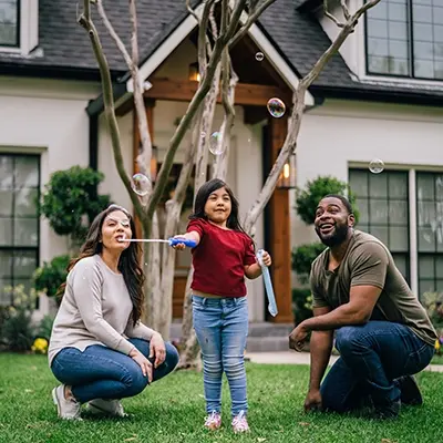 Family playing with bubble on front lawn of residential home.