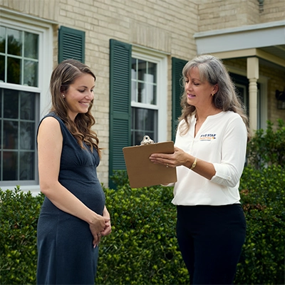 Female customer and painting professional discussing service details outdoors.