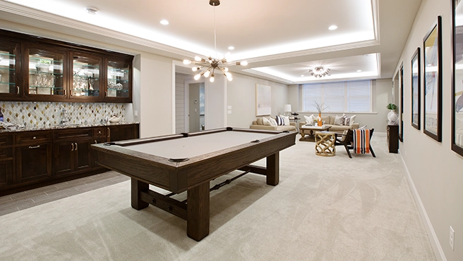 Finished basement with dark wood wet bar, pool table and dining table.