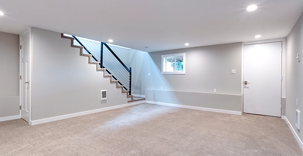 Carpeted, finished basement with grey painted walls.