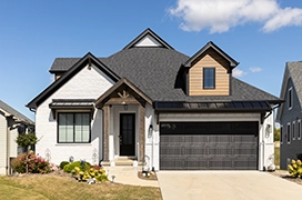 Exterior of a white brick home with dark colored trim and garage door.