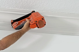 Five Star Painting professional using a nail gun on crown moulding. 