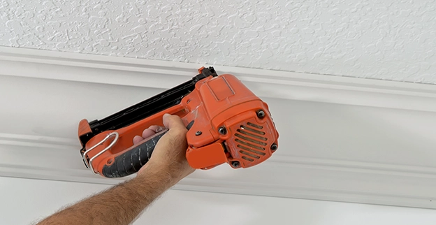 Five Star Painting professional using a nail gun on crown moulding.