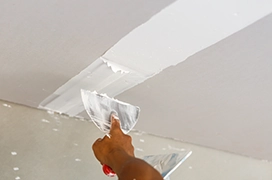 Five Star Painting professional adding mud to repair drywall on a ceiling.