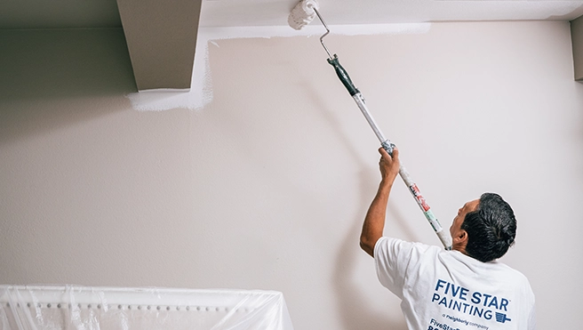 Five Star Painting professional using a roller to paint a ceiling.