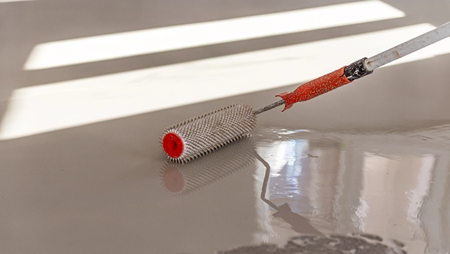 Five Star Painting professional with a roller staining a concrete floor.