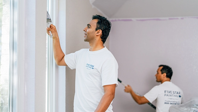 Five Star Painting professionals painting window trim.