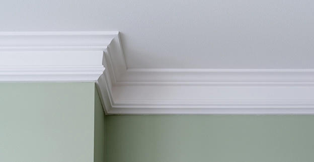 Photo of white crown molding against a green painted wall.