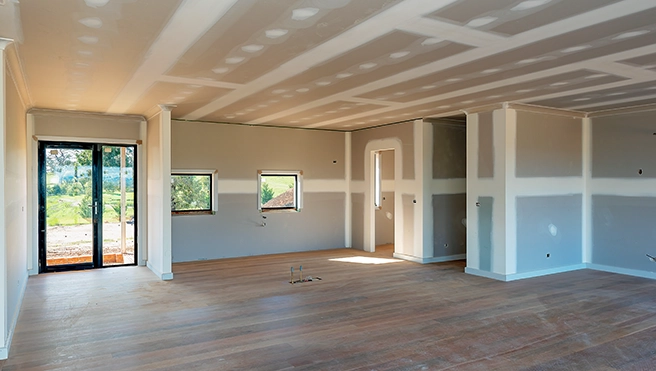 A grey painted interior room with fresh mud on the drywall for repairs.