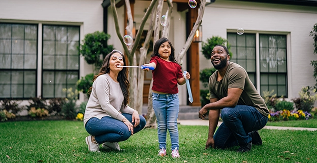 Happy family outside of their home playing with bubbles.