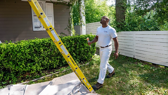 Five Star Painting professional walking up to a yellow ladder.
