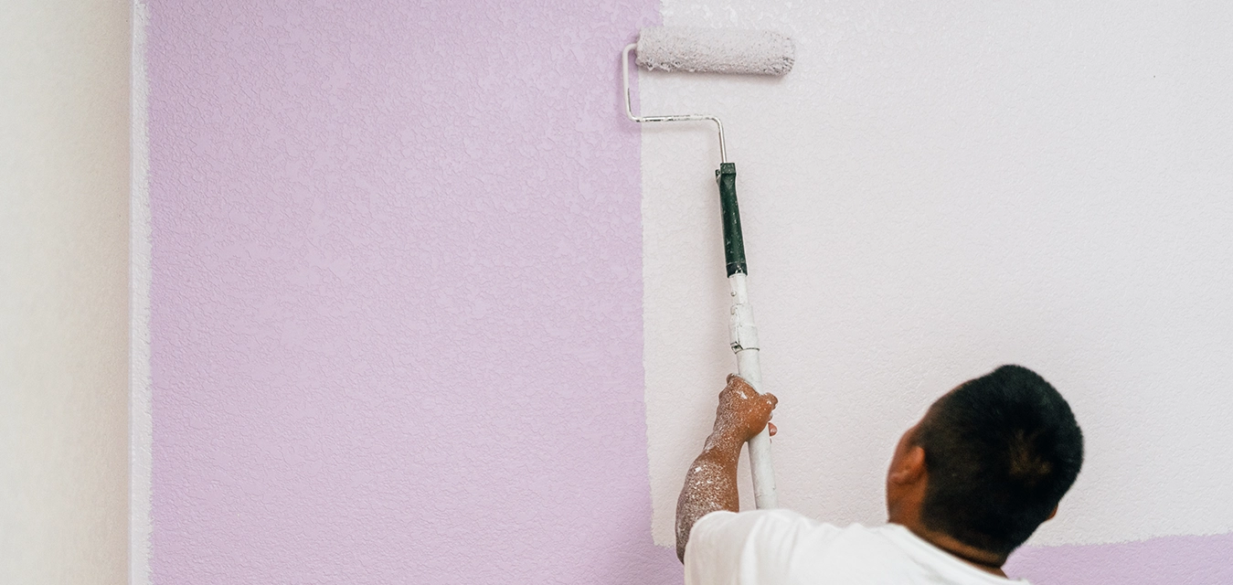 Five Star Painting professional holding paint roller with back to camera.
