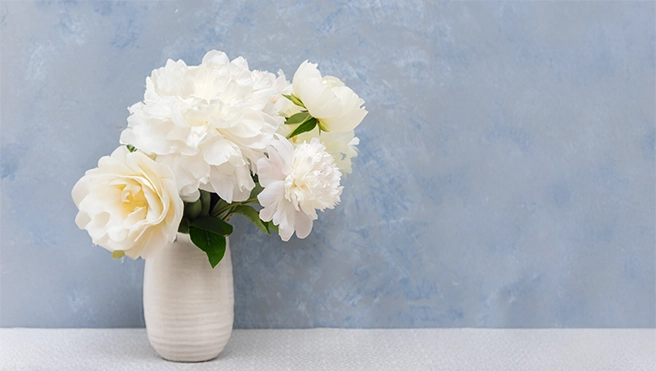 Blue texture painted wall with a vase of flowers on a ledge in front of it.