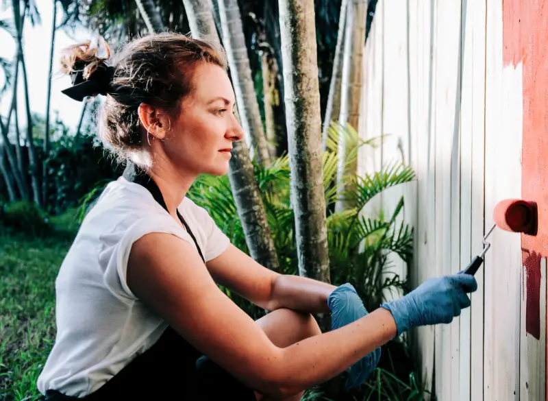 Woman painting a fence.