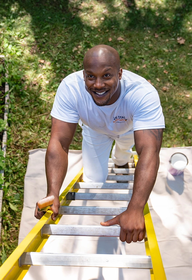 Smiling painting professional climbing ladder.