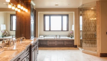 Photo of an expansive bathroom with warm colors, two sinks, a large tub, and a large shower.