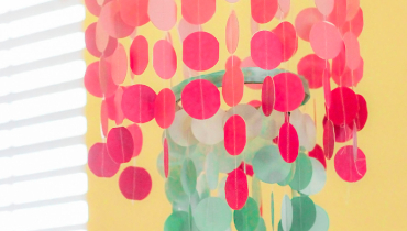 Photo of a colorful green and pink mobile against a yellow background