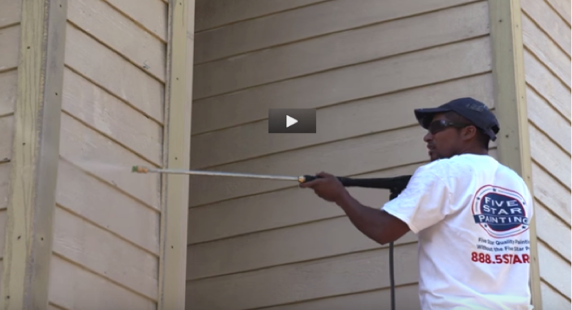 Photo of a Five Star Painting employee painting the outside of a house.