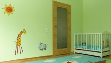 Photo of a brightly colored child's nursery with nature decals on the mint green wall