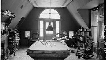 Black and white photo of a recreation room with a pool table