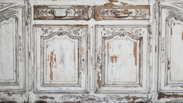 Vintage white commode bureau furniture with faded and some paint peeled off.