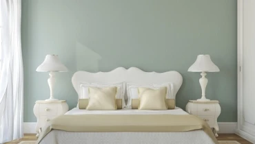 Photo of a bedroom with a sage green accent wall.